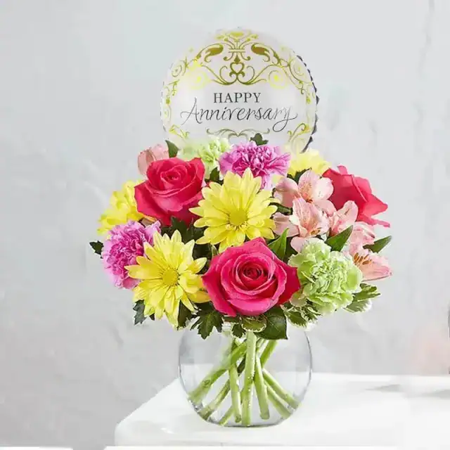4 Dark Pink Roses 3 Green Carnations 3 Purple Carnations 2 Stems of Pink Alstroemeria 2 stems of Yellow Daisies Pittosporum Leaves Arranged in a Fish Bowl 1 Foil Anniversary Foil Balloon